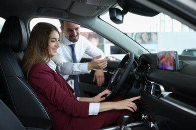 Happy salesman and client inside new car in salon