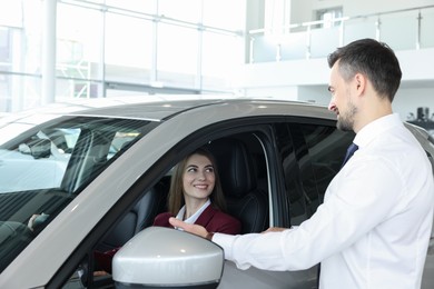 Happy salesman showing car to client in salon