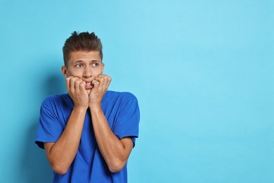 Photo of Emotional student having stress before exam on light blue background. Space for text