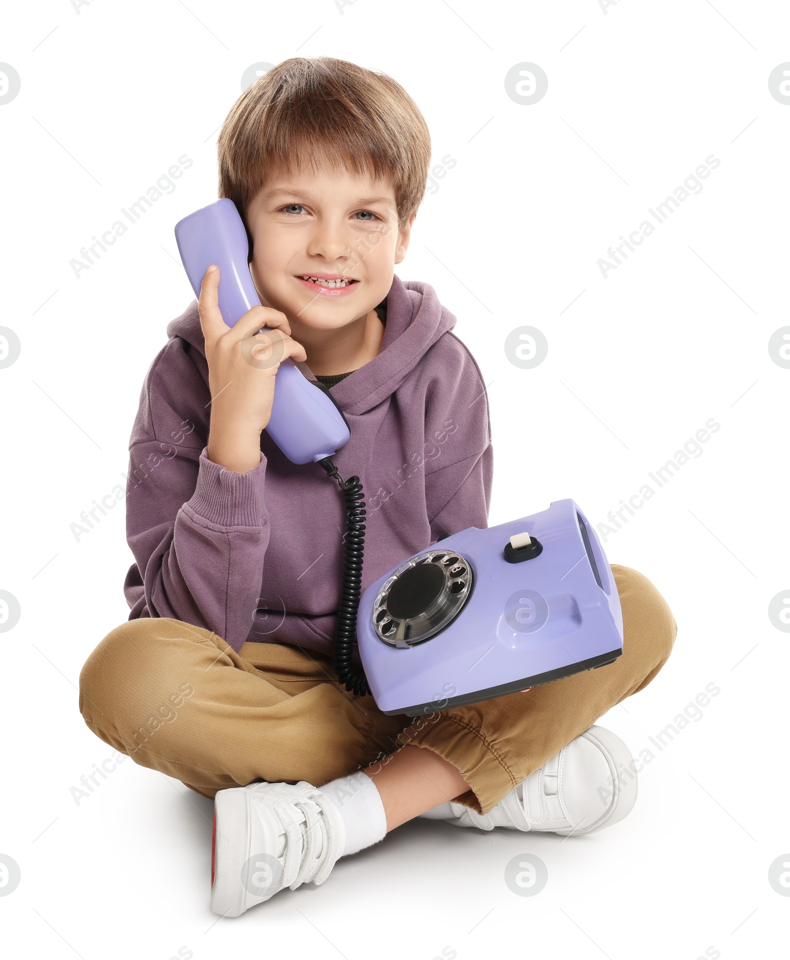 Photo of Cute little boy with old telephone on white background