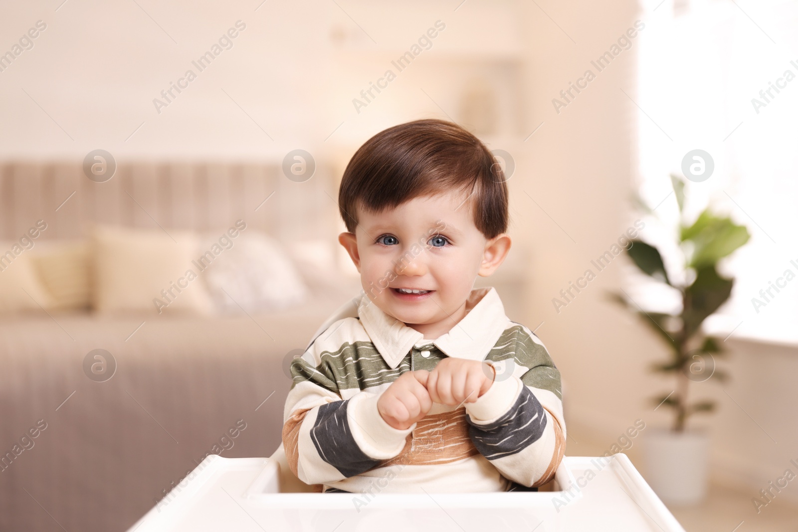 Photo of Cute little kid sitting in high chair at home