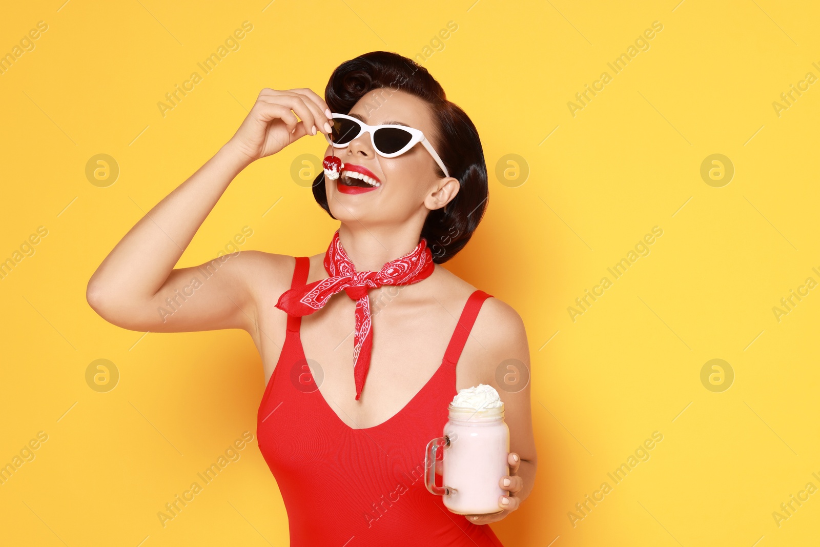 Photo of Pin-up woman in swimsuit with milk shake on orange background