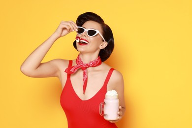 Photo of Pin-up woman in swimsuit with milk shake on orange background