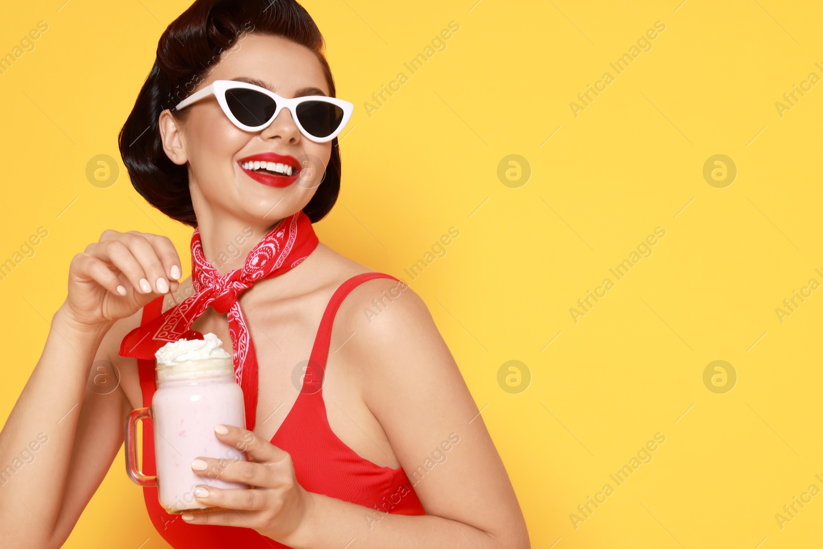 Photo of Pin-up woman in swimsuit with milk shake on orange background, space for text