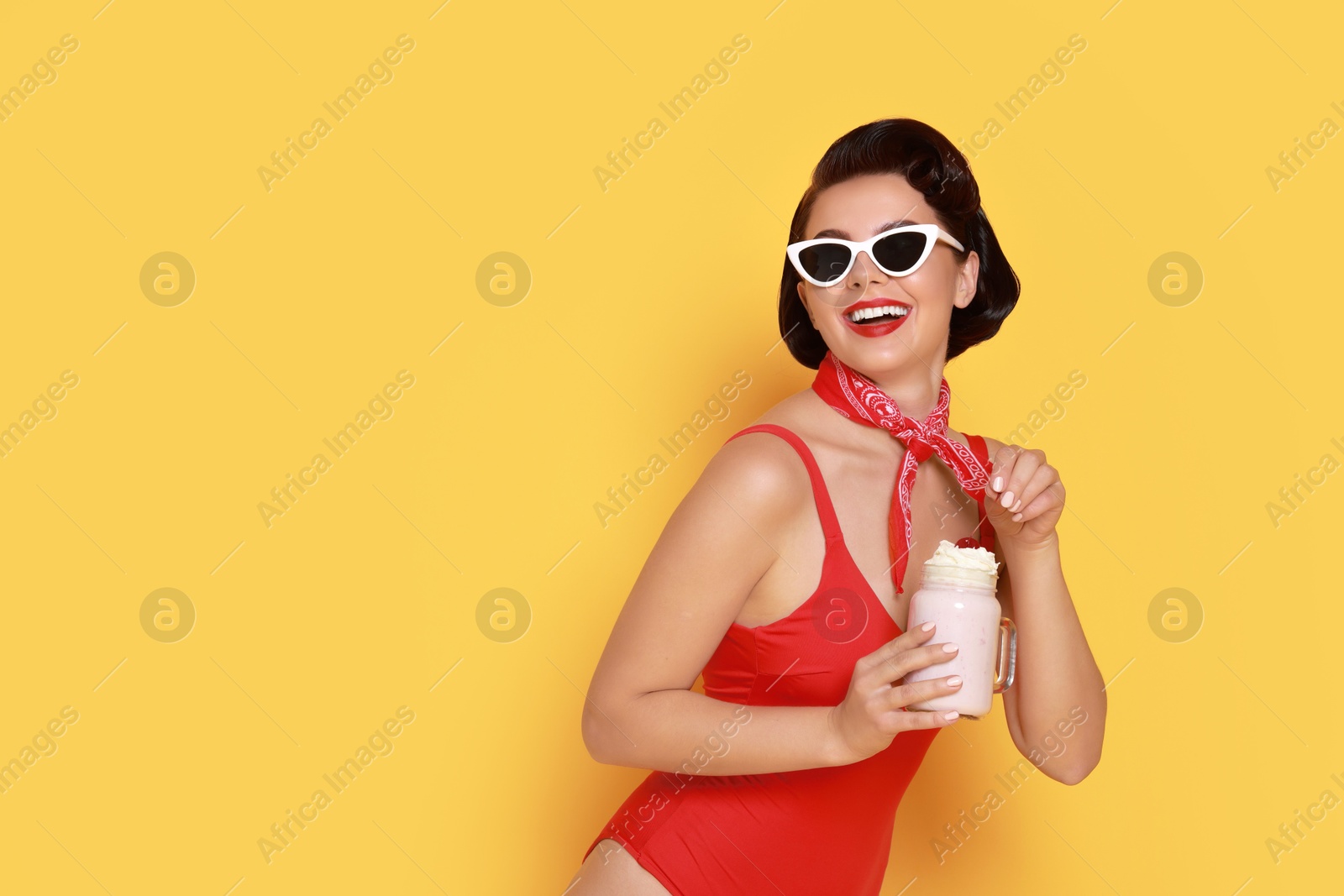 Photo of Pin-up woman in swimsuit with milk shake on orange background, space for text