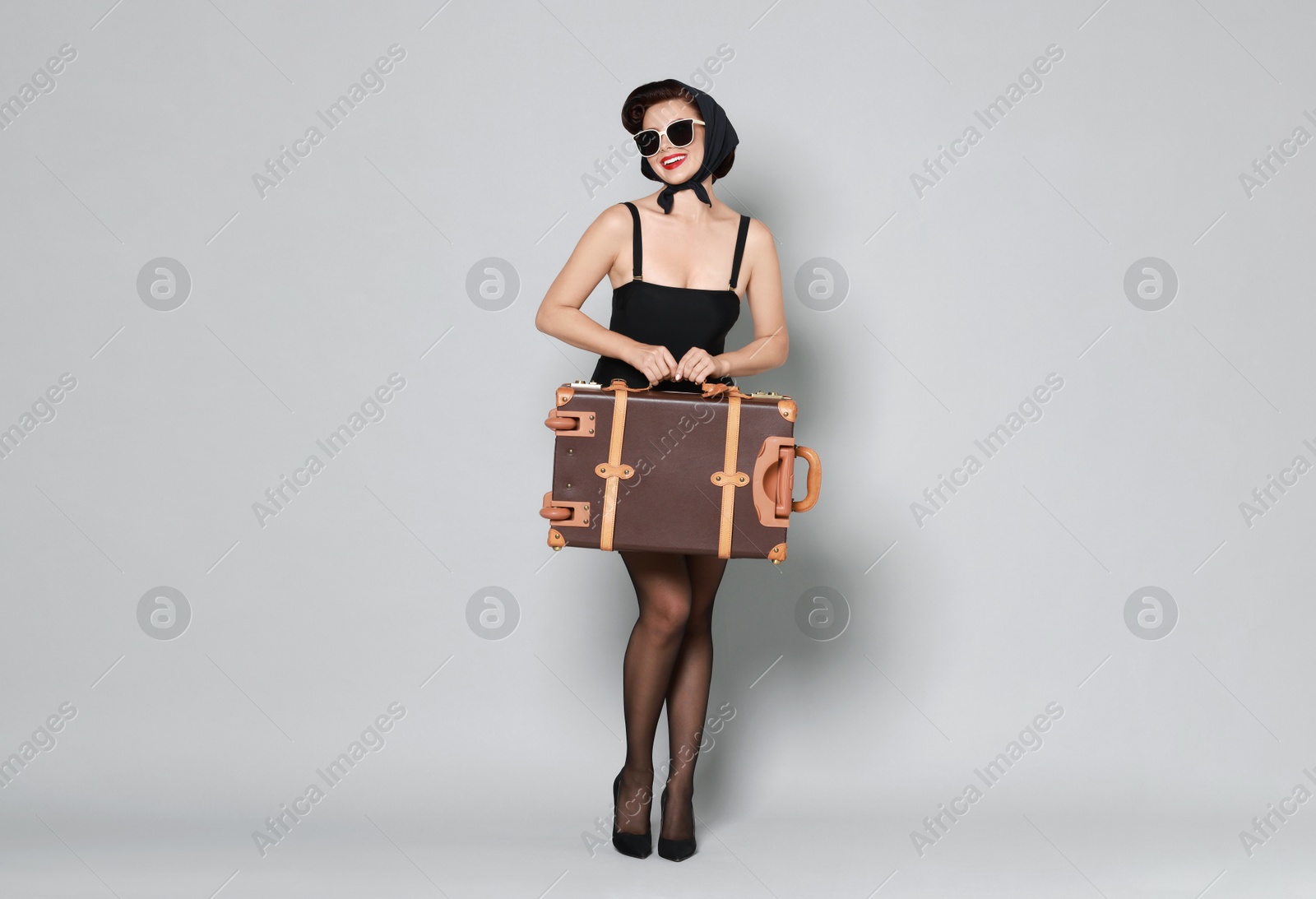 Photo of Pin-up woman with suitcase on grey background