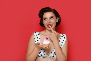 Photo of Pin-up woman in bikini with cupcake on red background