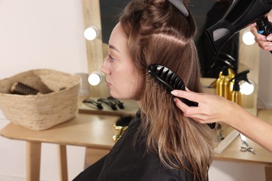 Photo of Hairdresser blow drying client's hair in salon, closeup