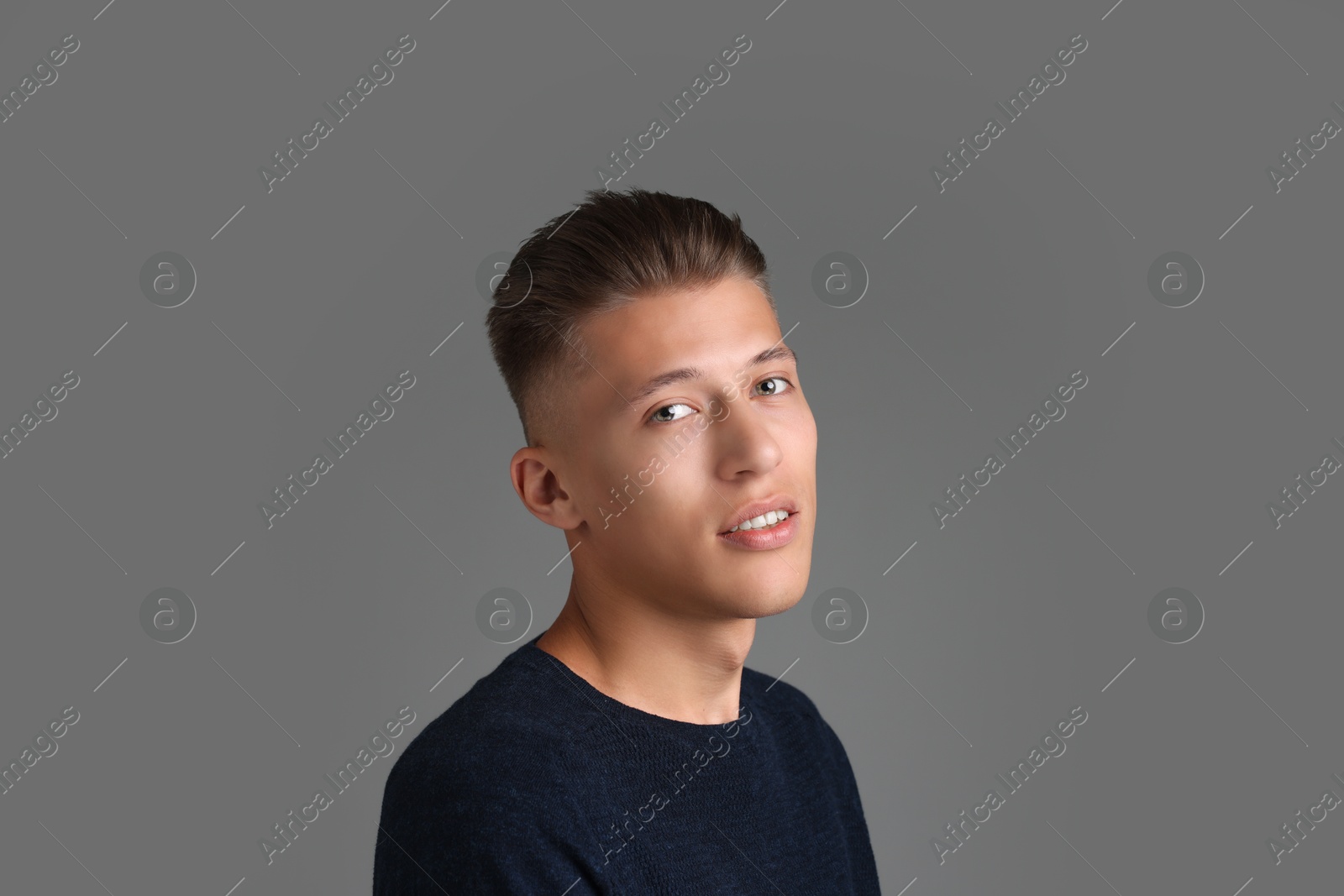 Photo of Handsome young man with stylish haircut on grey background