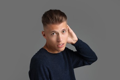 Photo of Handsome young man with stylish haircut on grey background