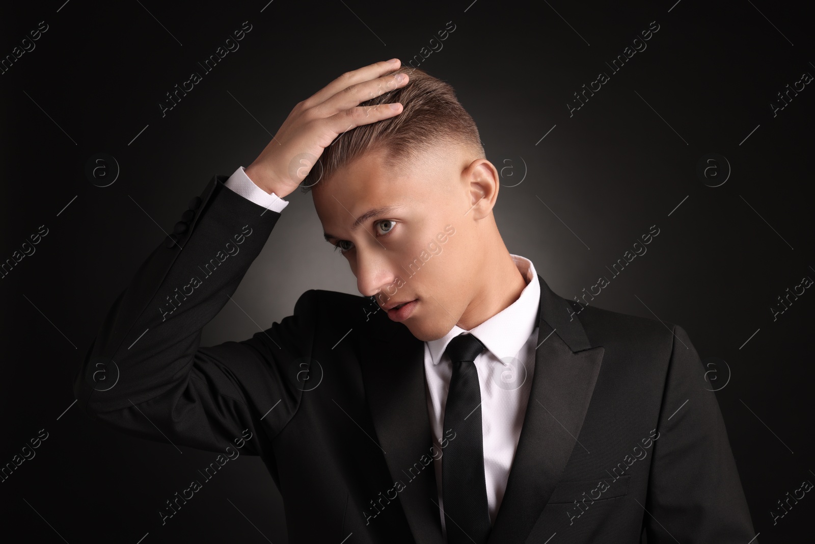 Photo of Confident young man with stylish haircut on black background