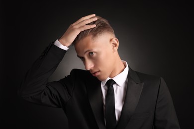 Photo of Confident young man with stylish haircut on black background