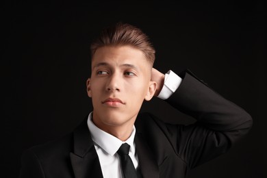 Photo of Confident young man with stylish haircut on black background