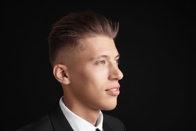 Photo of Confident young man with stylish haircut on black background