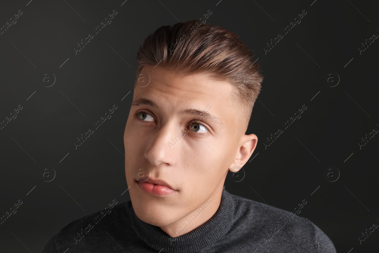 Photo of Handsome young man with stylish haircut on black background