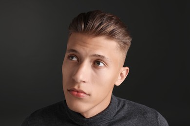 Photo of Handsome young man with stylish haircut on black background