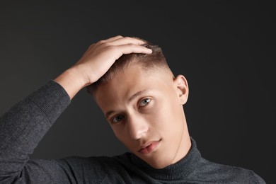 Photo of Confident young man with stylish haircut on black background