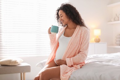 Photo of Portrait of beautiful pregnant with cup of drink on bed at home