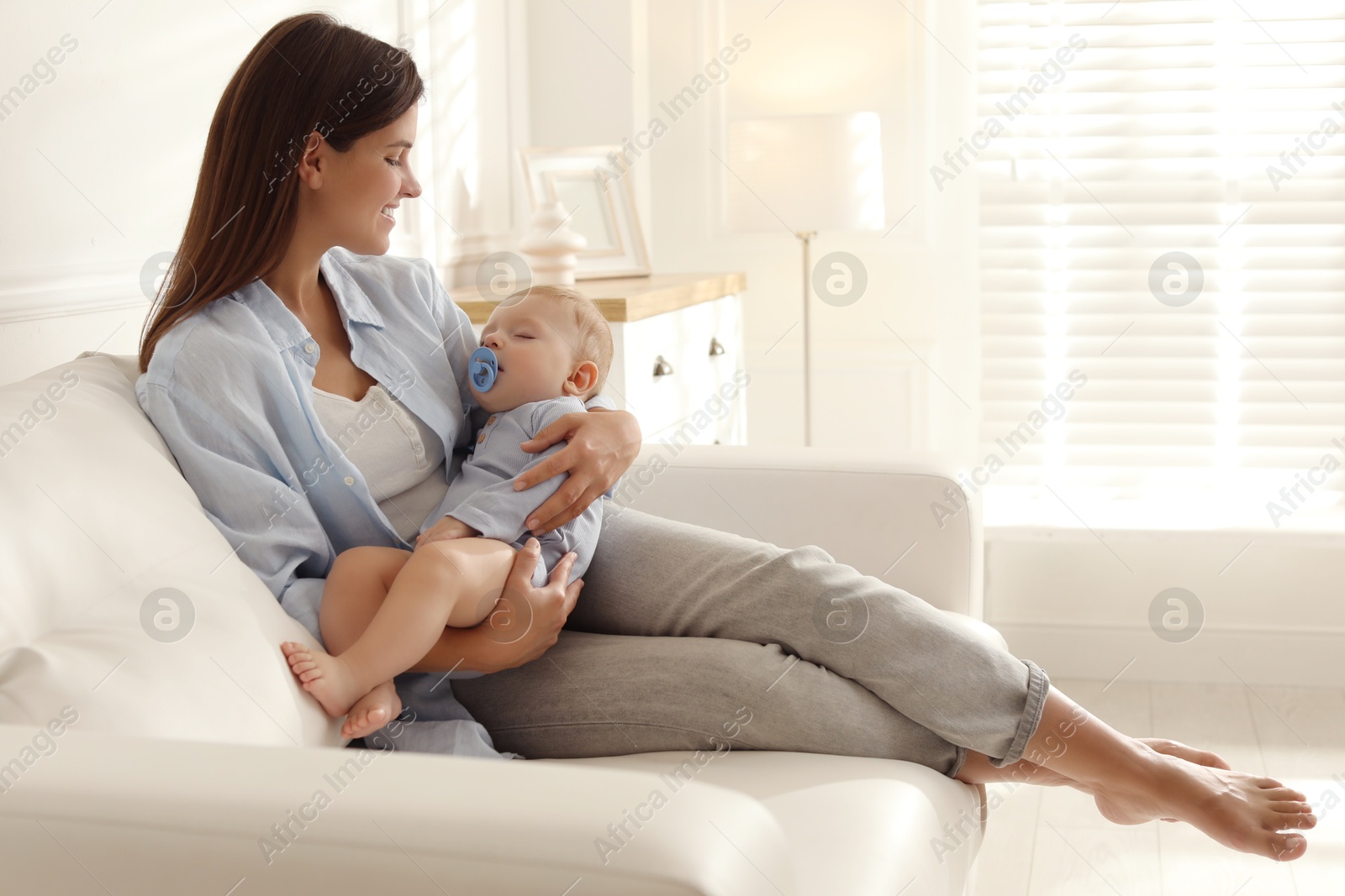 Photo of Mother with her sleeping baby on sofa at home. Space for text