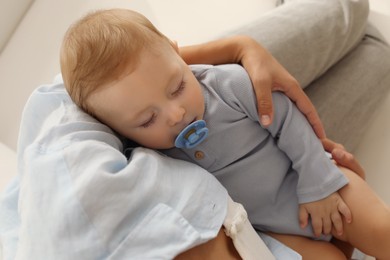 Photo of Mother with her sleeping baby on sofa indoors, closeup