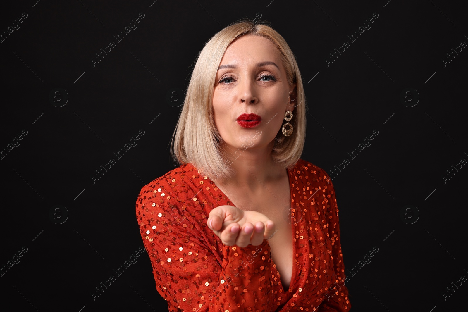 Photo of Woman with perfect makeup sending air kiss on black background