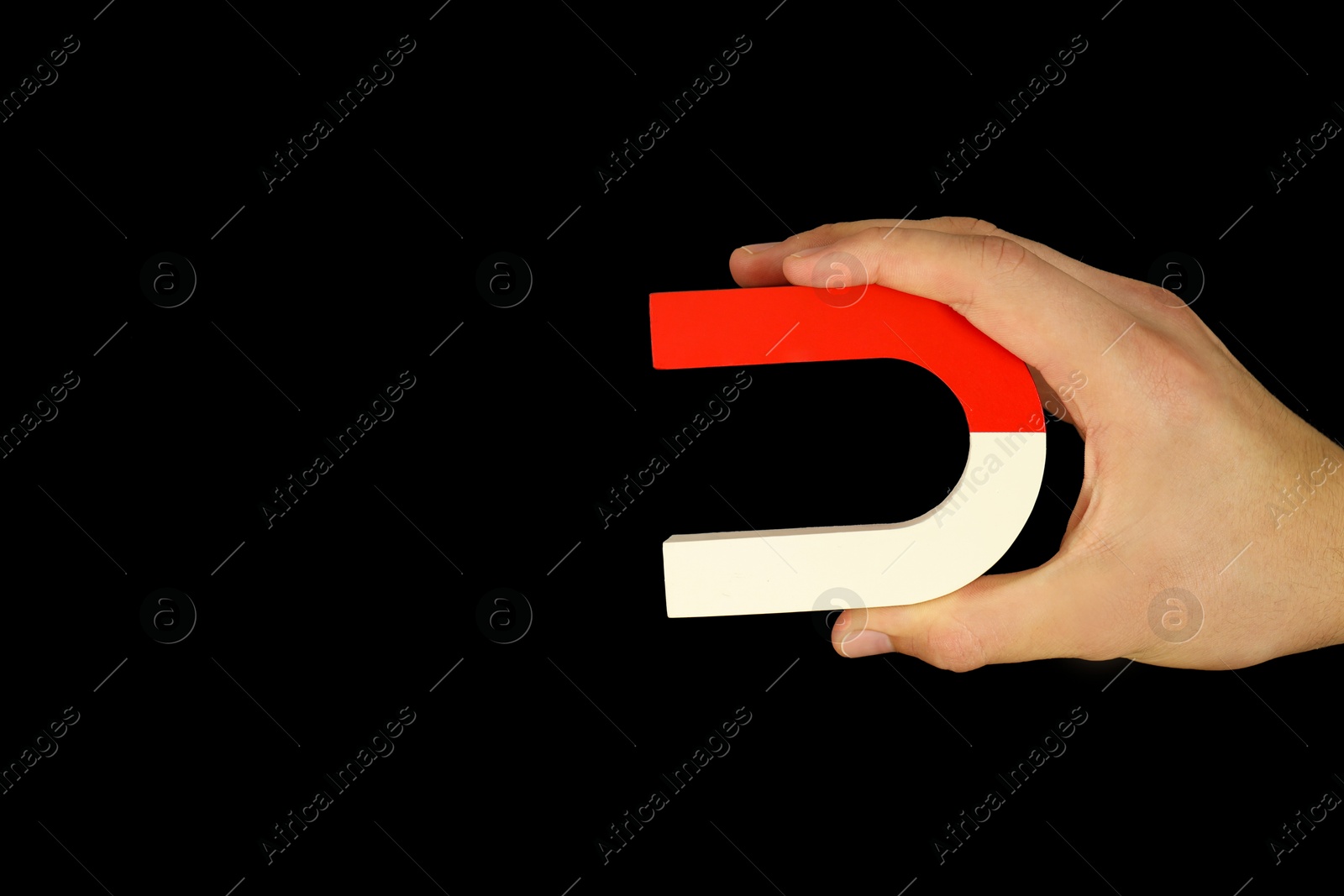 Photo of Man holding horseshoe magnet on dark background, closeup. Space for text