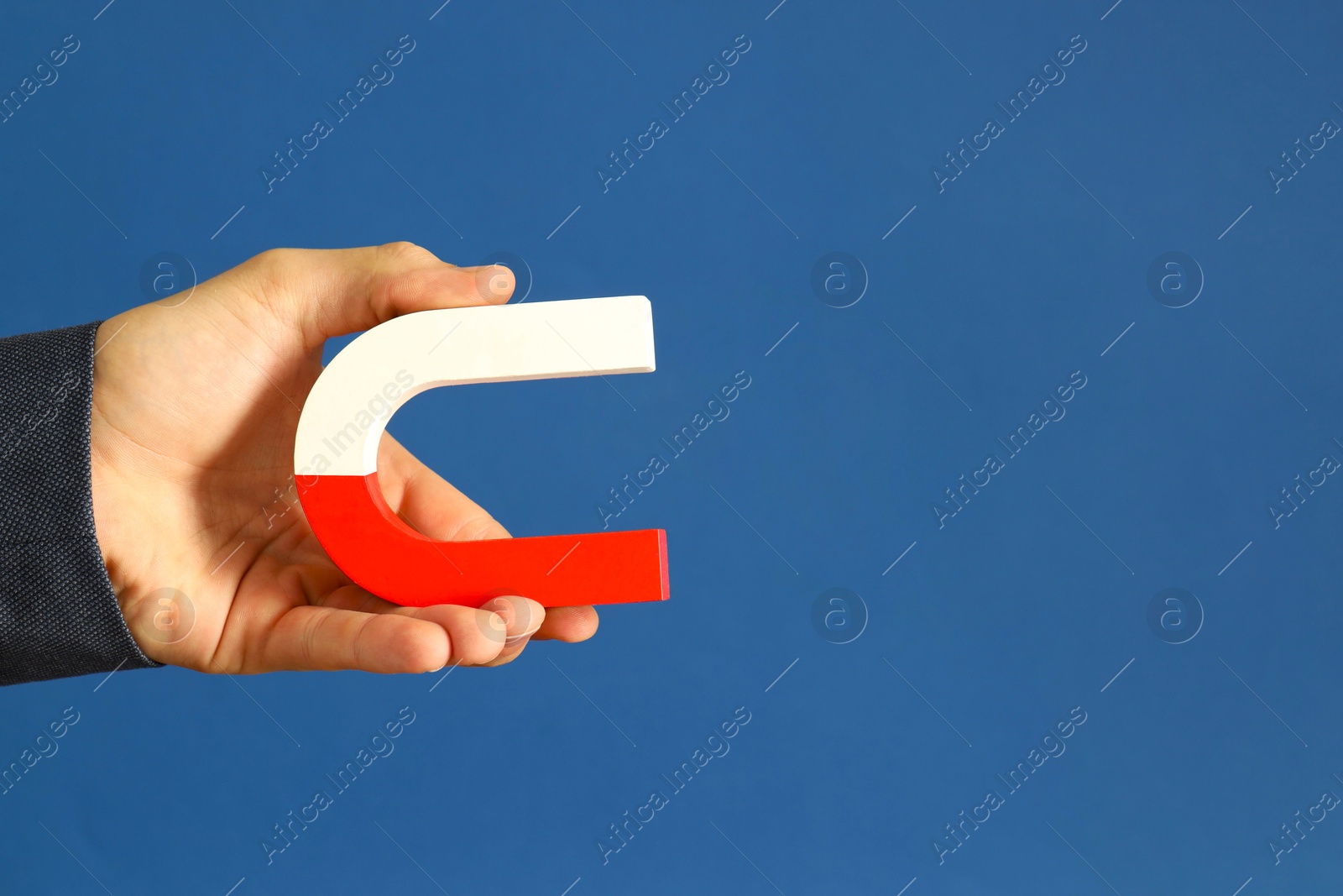 Photo of Man holding horseshoe magnet on blue background, closeup. Space for text