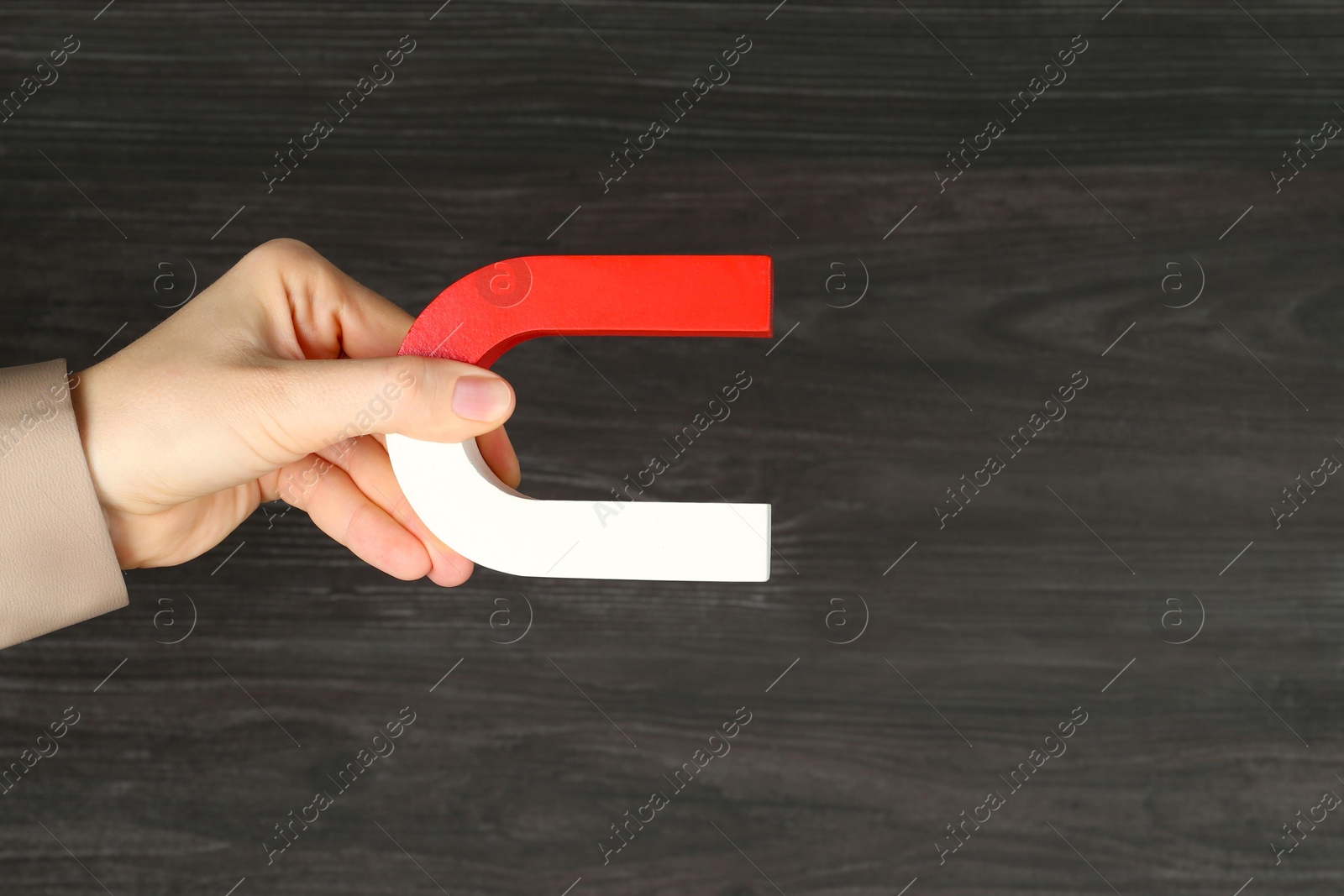 Photo of Woman with horseshoe magnet on wooden background, closeup