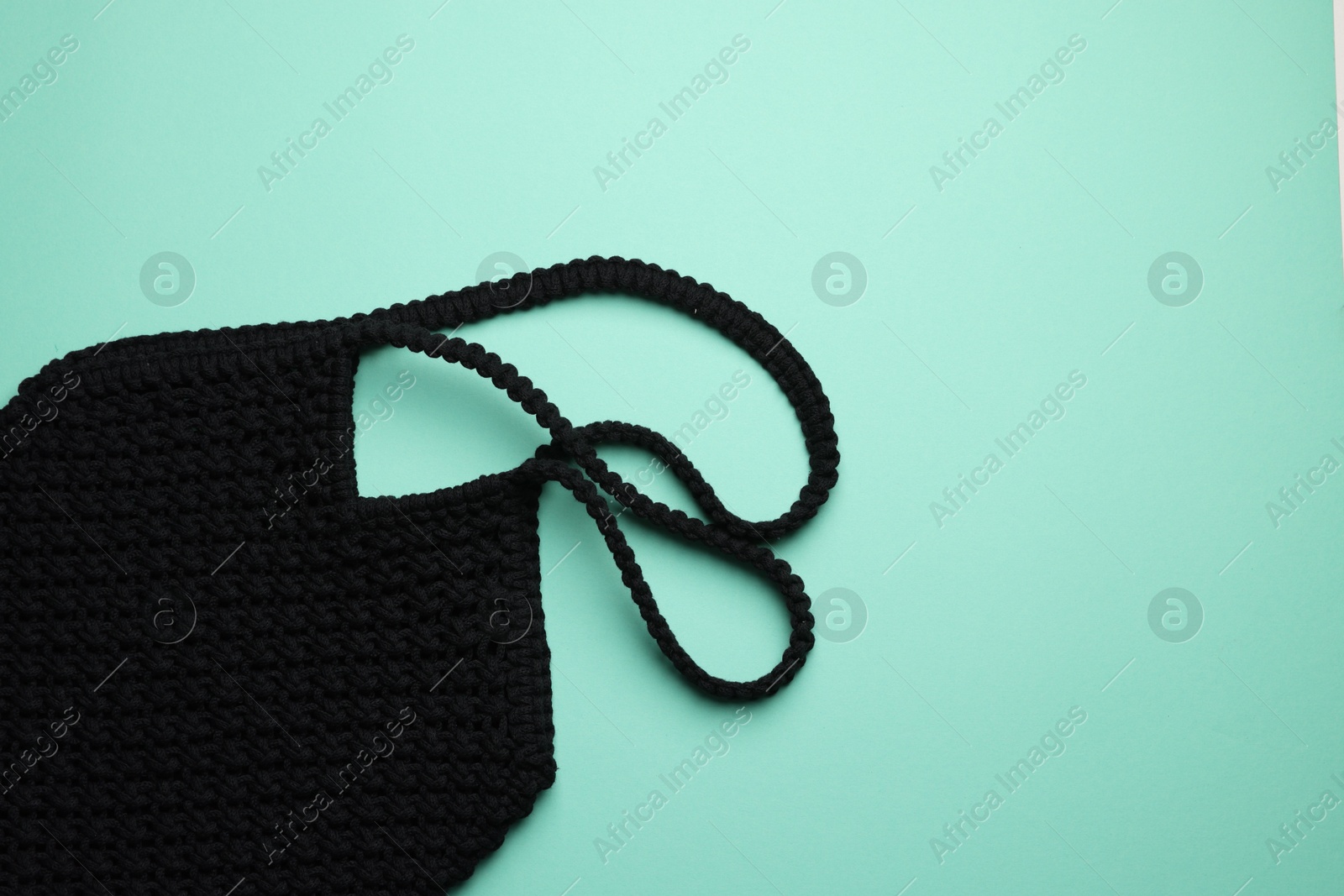 Photo of Macrame shopping bag on turquoise background, top view. Space for text