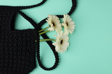 Photo of Macrame shopping bag with beautiful flowers on turquoise background, top view. Space for text