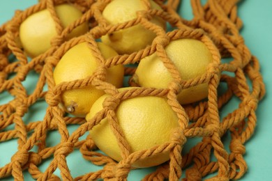 Photo of Macrame shopping bag with lemons on turquoise background, closeup