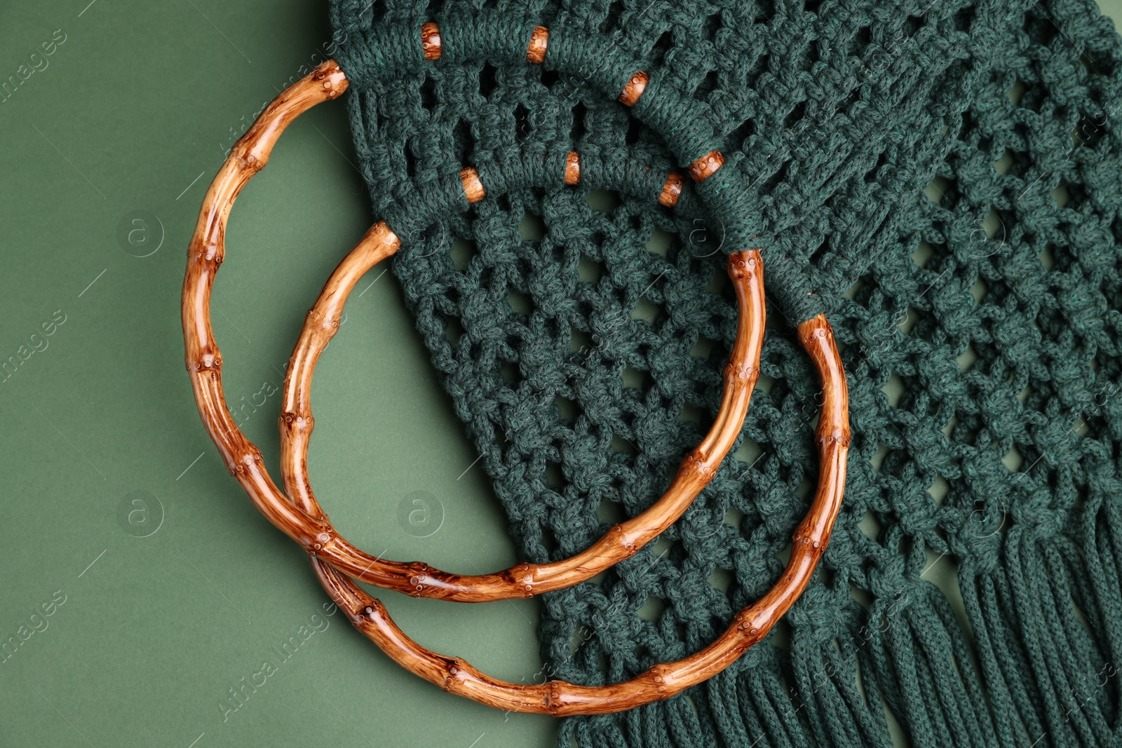 Photo of Macrame shopping bag with wooden handles on green background, top view