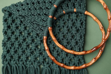 Photo of Macrame shopping bag with wooden handles on green background, top view