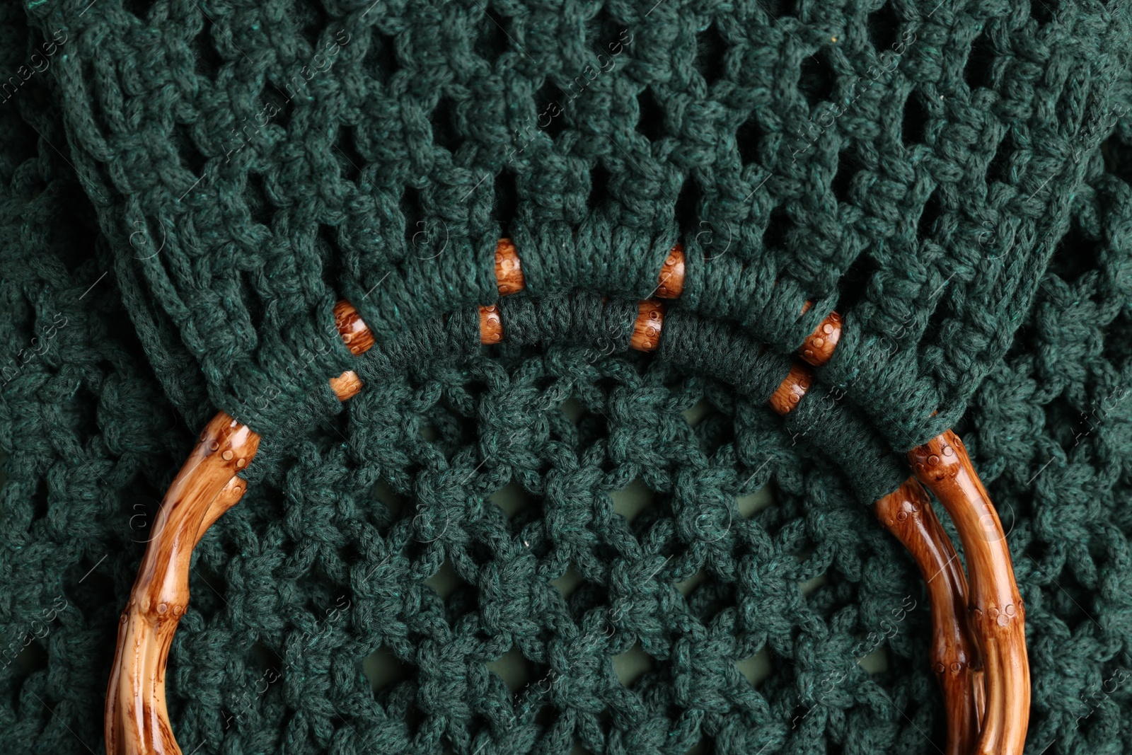 Photo of Macrame shopping bag with wooden handles as background, top view