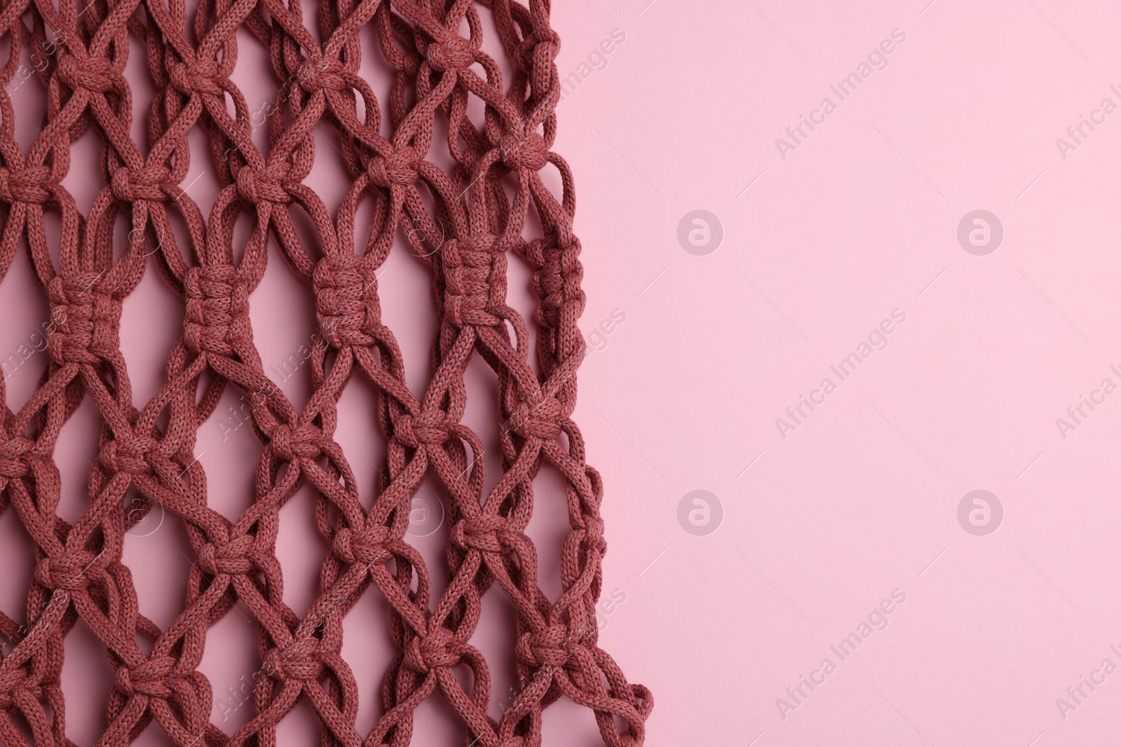 Photo of Macrame shopping bag on pink background, top view. Space for text