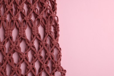 Photo of Macrame shopping bag on pink background, top view. Space for text