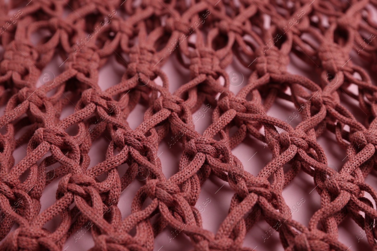 Photo of Macrame shopping bag on pink background, closeup