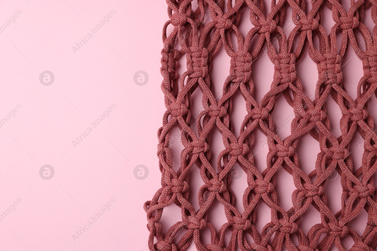 Photo of Macrame shopping bag on pink background, top view. Space for text