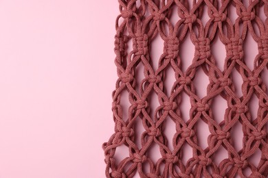 Photo of Macrame shopping bag on pink background, top view. Space for text