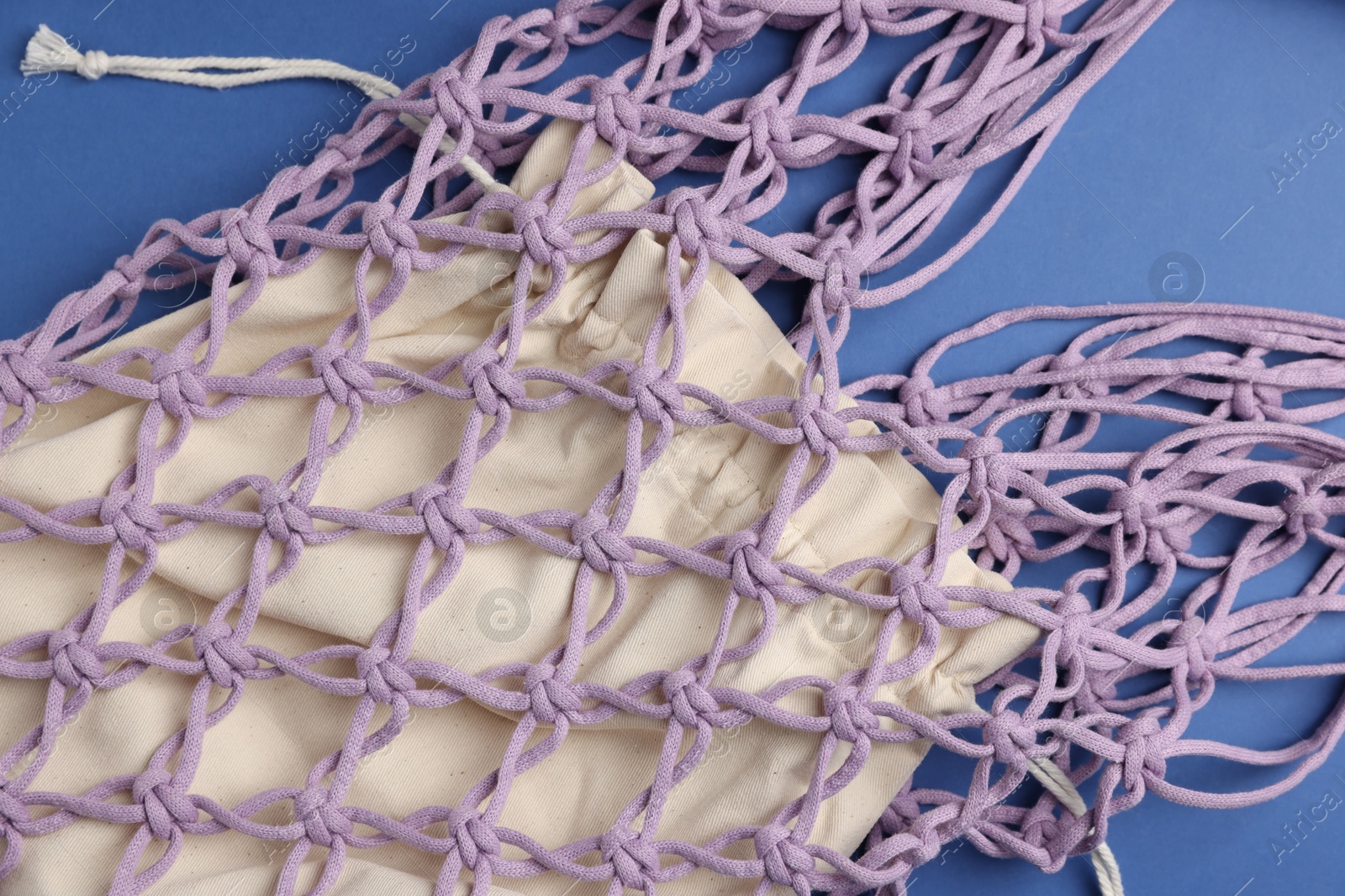 Photo of Macrame shopping bag on blue background, above view