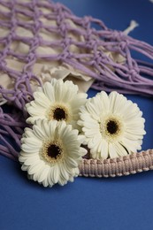 Photo of Macrame shopping bag with flowers on blue background, closeup