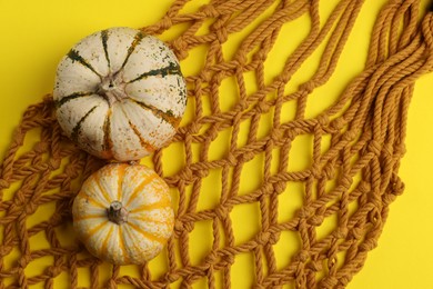 Photo of Macrame shopping bag and pumpkins on yellow background, top view