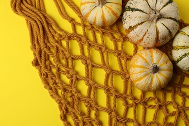 Photo of Macrame shopping bag and pumpkins on yellow background, top view