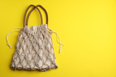 Photo of Macrame shopping bag on yellow background, top view. Space for text