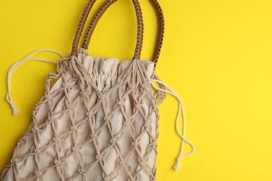 Photo of Macrame shopping bag on yellow background, top view. Space for text