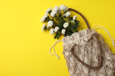 Photo of Macrame shopping bag with flowers on yellow background, top view. Space for text