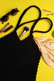 Flat lay composition with macrame shopping bag and makeup products on yellow background