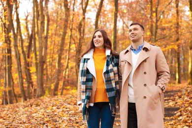 Photo of Happy couple spending time together in autumn park, space for text