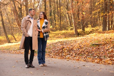 Photo of Happy couple spending time together in autumn park, space for text