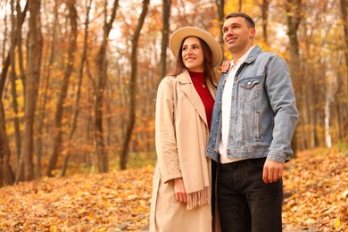 Photo of Happy couple spending time together in autumn park, space for text